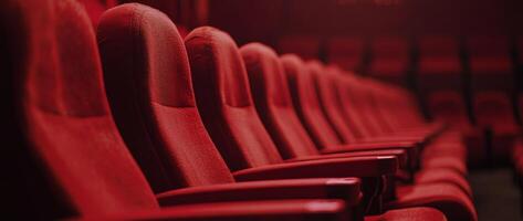 Empty red theater seats await moviegoers in a dimly lit cinema setting photo