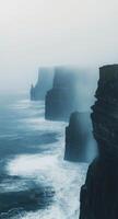 Misty cliffs and crashing waves along the rugged coast at Cliffs of Moher in Ireland photo