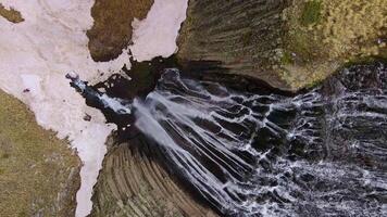 A powerful stream of water flows beautifully down the volcanic rocks. Top down video