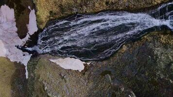 Aerial view of the flow of water falling from the high cliffs. Top down video