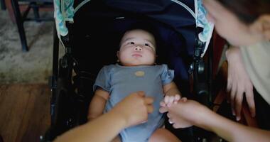 Handheld selective focus shot, Two happy women playing with a little boy lying in a baby stroller. Family enjoying happy time together. Happy lifestyle. video