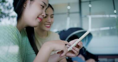 Handheld selective focus shot, Two happy siblings sit at a table playing social media together on smartphone while waiting for little boy to wake up. Family enjoying happy time together. video