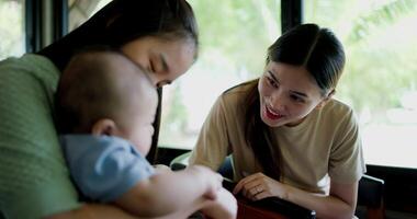Handheld selective focus shot, Two happy women having fun playing with a little boy in a coffee shop. Family enjoying time together. Happy lifestyle. video