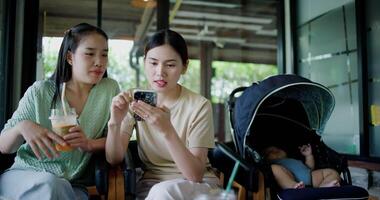 Handheld selective focus shot, Two happy siblings sit at a table playing social media together on smartphone while waiting for little boy to wake up. Family enjoying happy time together. video