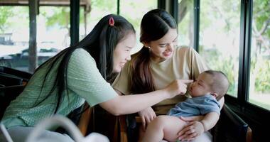 Handheld selective focus shot, Two happy women having fun playing with a little boy in a coffee shop. Family enjoying time together. Happy lifestyle. video