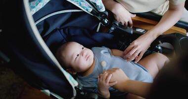 Handheld selective focus shot, Two happy women playing with a little boy lying in a baby stroller. Family enjoying happy time together. Happy lifestyle. video