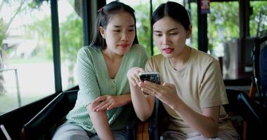Handheld selective focus shot, Two siblings are playing social media together on smartphone while sitting at a table in a cafe. Family enjoying happy time together. video