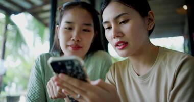 Handheld selective focus shot, Two siblings are playing social media together on smartphone while sitting at a table in a cafe. Family enjoying happy time together. video