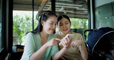 Handheld selective focus shot, Two happy siblings sit at a table playing social media together on smartphone while waiting for little boy to wake up. Family enjoying happy time together. video