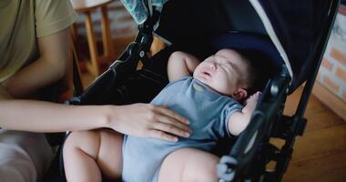 Handheld selective focus shot, Young mother happily playing with little boy sleeping in baby stroller in a cafe. Family enjoying happy time together. Happy lifestyle. video