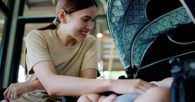 Footage of handheld shot, Young mother happily playing with little boy lying in baby stroller in a cafe. Family enjoying happy time together. Happy lifestyle. video