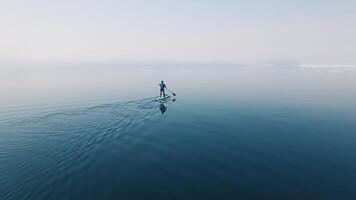Drone view of a sup surfer floats through the ice capturing serenity. video