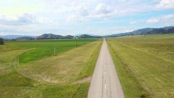 Aerial view of the car driving along an asphalt road among green fields of road video
