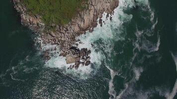 View from a drone vertically down on a stone cape washed by strong waves video