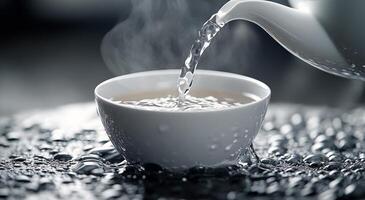 Pouring hot tea into a white cup surrounded by scattered tea leaves in a dimly lit setting photo