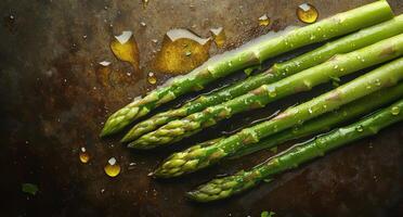Freshly washed asparagus with water droplets on a dark textured surface photo