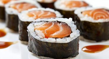 Fresh sushi rolls with salmon and sesame drizzled with sauce on a plate photo