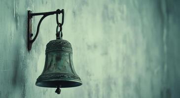 Rustic bronze bell hanging from a branch with blurred background of autumn leaves during daylight photo