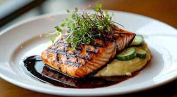 Grilled salmon fillet with fresh herbs and vegetables served on a white plate at a restaurant photo