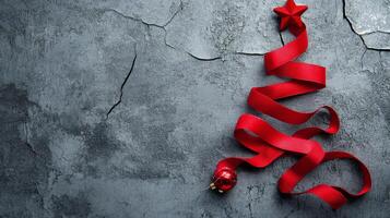 A decorative red ribbon forming a Christmas tree shape on a textured gray background photo