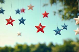 Colorful hanging stars in red, white, and blue against a bright blue sky at a festive outdoor event photo
