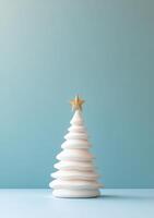 White ceramic Christmas tree decoration on a soft blue background in a minimalist style photo