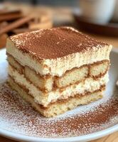 Delicious homemade tiramisu dessert served on a white plate with cocoa powder topping photo
