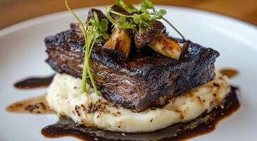 Beef tenderloin with roasted mushrooms on creamy mashed potatoes at a gourmet restaurant photo