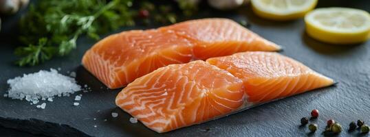 Fresh salmon fillets prepared with herbs and garnished with lemon slices and salt crystals photo