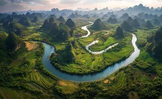 Aerial view of winding river surrounded by green fields and mountains in a serene landscape at dusk photo