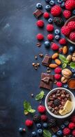 A colorful arrangement of fresh berries, nuts, and chocolate on a textured dark surface photo