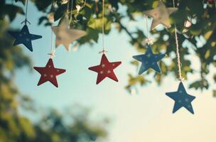Colorful stars hanging against a clear sky while sunlight filters through the leaves photo