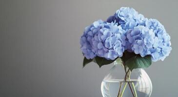 Blue hydrangeas in a clear vase displayed on a marble table against a textured gray background photo
