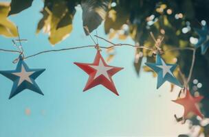 Colorful stars hanging against a clear sky while sunlight filters through the leaves photo