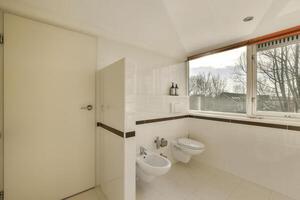 A bathroom with a window and a toilet photo
