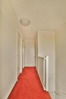 A hallway with a red carpet and white walls photo