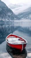 Serene red boat floating in calm lake surrounded by misty mountains in early morning light photo