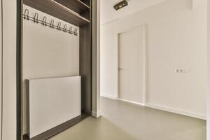 A white hallway with a coat rack and a door photo