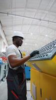 African american worker entering data in CNC machine at pvc window factory to get the production going video