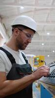 Worker On Factory Analyzes The Production Process And Programming Industrial CNC Machine Tool. Vertical video