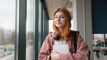 Portrait of happy girl student with books in hands in the university building. Back to school video