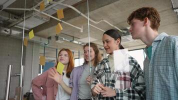 Group of students while working together during brainstorming and standing behind glass wall with sticky colorful papers video