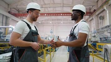 Two diverse factory workers talking and handshake near production line on PVC factory video