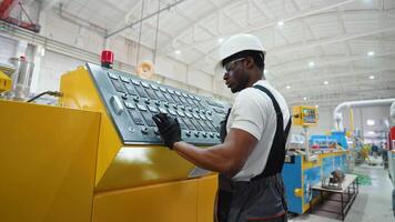 Black worker entering data in CNC machine at pvc window factory to get the production going video