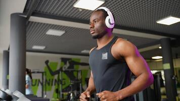 A man with headphones running in a modern gym on a treadmill video