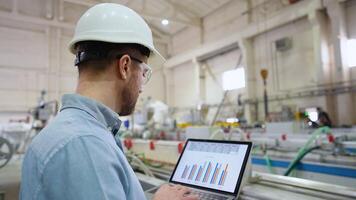 Industrial engineer programmer checking the production line with laptop at windows factory. Factory for aluminum and PVC windows and doors production video