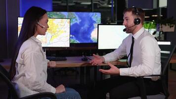 Two delivery operators sitting at desk in office monitoring cargo transportation and giving high five doing great job video