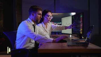Creative team of traders are having a conversation in a dark office with display screens. Analyzing data, graphs and reports for investment purposes video