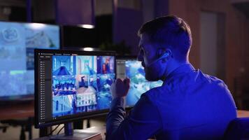 Security system operator looking at CCTV footage at desk in control room video