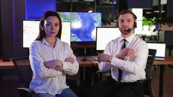 Portrait of two transport dispatchers with headsets in modern electronic control room. In the background monitors show various maps. video